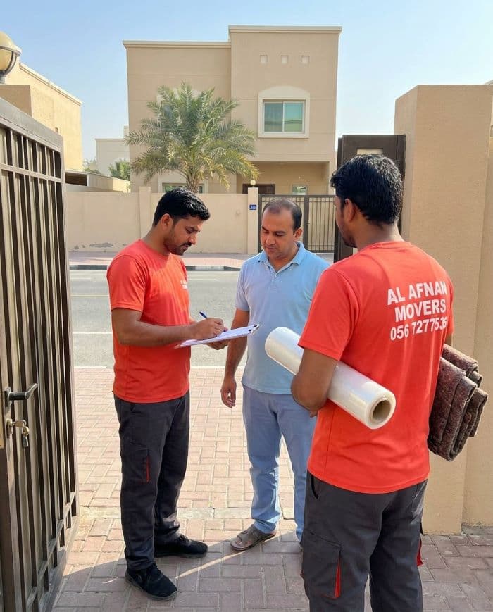 Al Afnan movers confirming move details with a customer outside a Sharjah villa