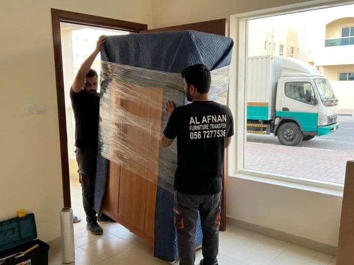 Furniture movers in Sharjah carefully wrapping and transporting individual furniture items